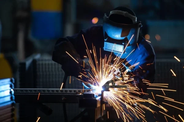 A person welding in the dark with sparks flying.